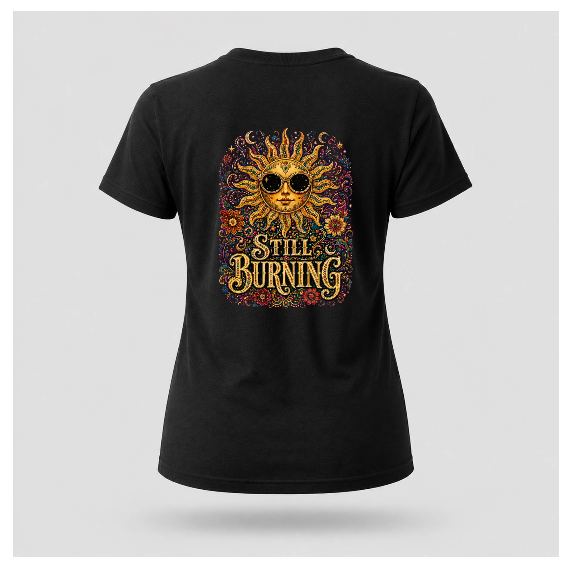 Back of a floating female form wearing the Black Still Burning Sun Spirit Tee featuring an ornate celestial sun with floral artwork and the words "Still Burning" by RIOTTEES.