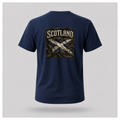 Male model wearing a navy blue Gildan 5000 t-shirt featuring the Modern Scotland design on the back, showing a distressed Saltire layered over weathered tartan beneath bold Scotland lettering by RIOTTEES.