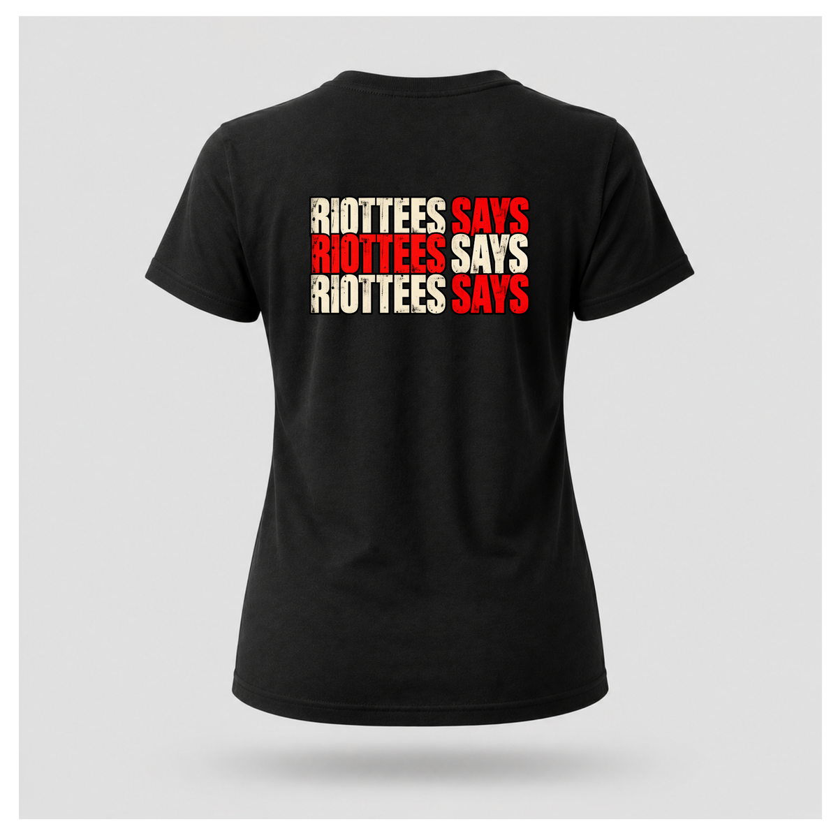 Women's black RIOTTEES T-shirt featuring repeated RIOTTEES SAYS typography across the upper back in distressed red and off-white.