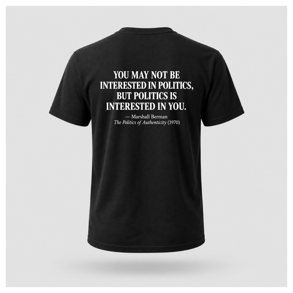 Male model wearing a black Politics Is Interested In You T-shirt with the Marshall Berman political quote printed in distressed white text across the back.