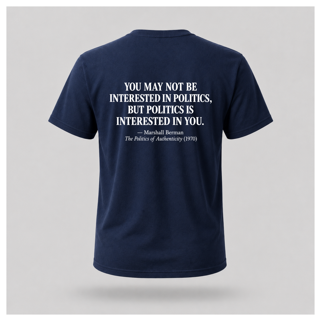 Male model wearing a navy blue Politics Is Interested In You T-shirt, showing the distressed white Marshall Berman quote on the back.
