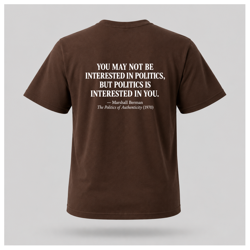Male model wearing a chocolate brown Politics Is Interested In You T-shirt, displaying the distressed white Marshall Berman quote on the back.