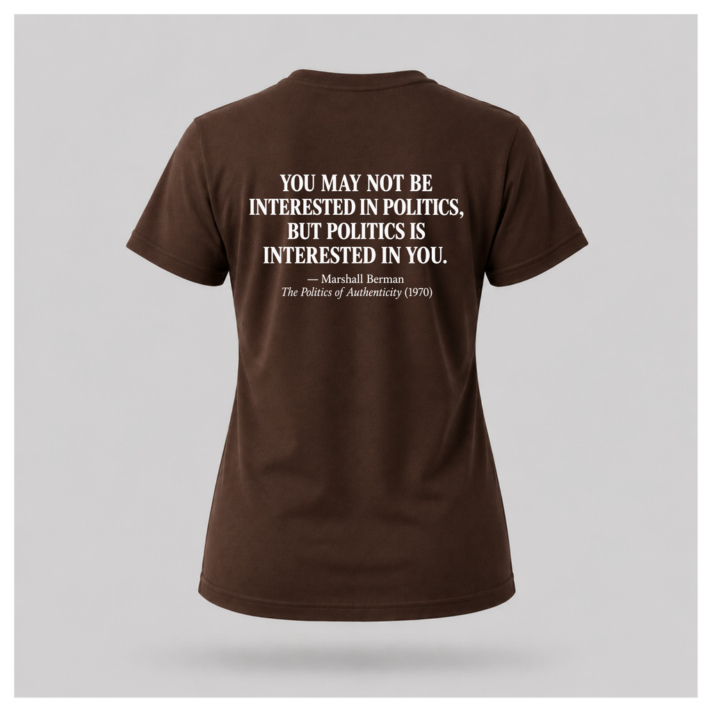 Female model wearing a chocolate brown Politics Is Interested In You T-shirt, displaying the distressed white Marshall Berman quote on the back.
