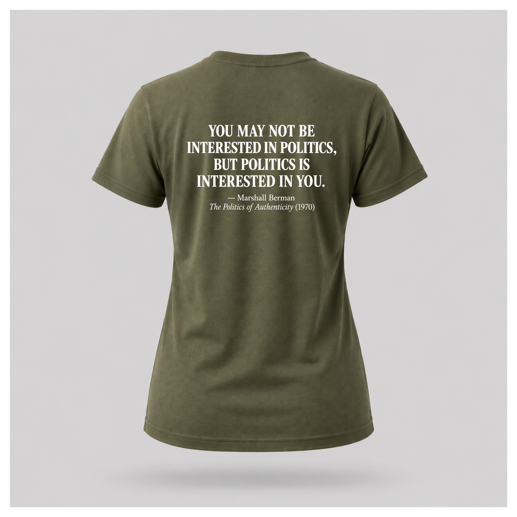 Female model wearing a military green Politics Is Interested In You T-shirt with the distressed white Marshall Berman quote printed on the back.
