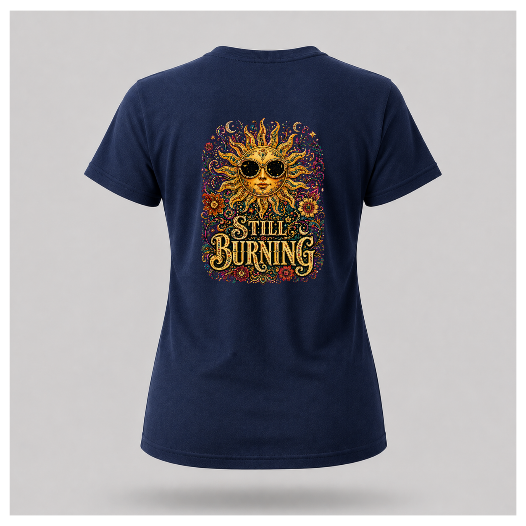 Back of a floating female form wearing the Navy Blue Still Burning Sun Spirit Tee featuring an ornate celestial sun with floral artwork and the words "Still Burning" by RIOTTEES.