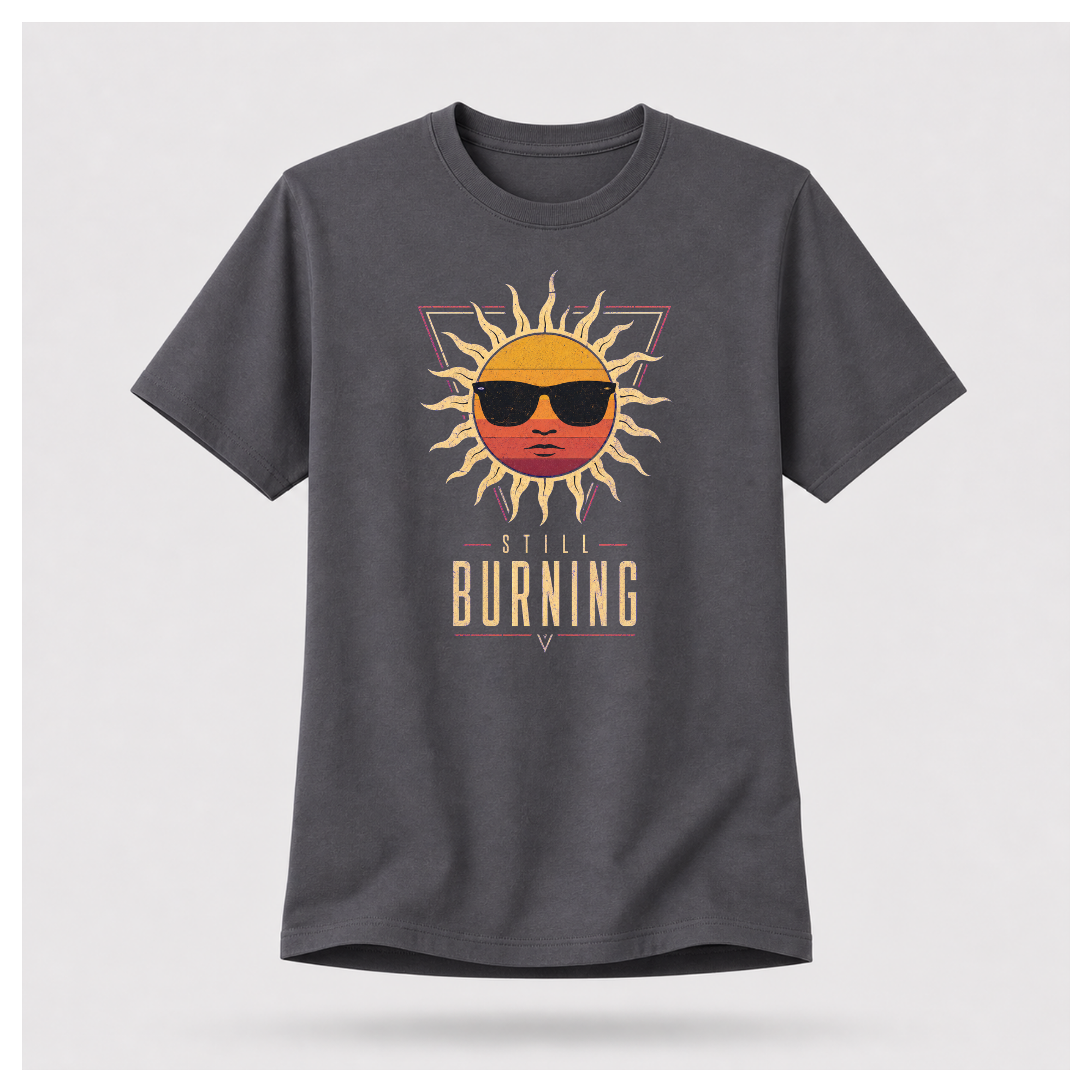 Floating male form wearing the Charcoal Grey Still Burning Sunset Prism Gildan 5000 T-shirt featuring the vintage sunset face wearing sunglasses graphic with Still Burning typography by RIOTTEES.
