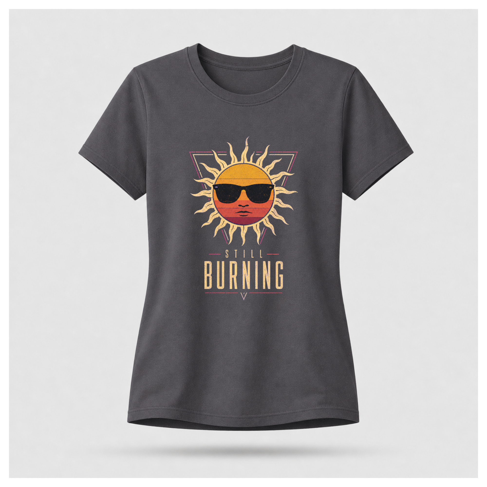 Floating female form wearing the Charcoal Grey Still Burning Sunset Prism Gildan 5000 T-shirt featuring the vintage sunset face wearing sunglasses graphic with Still Burning typography by RIOTTEES.
